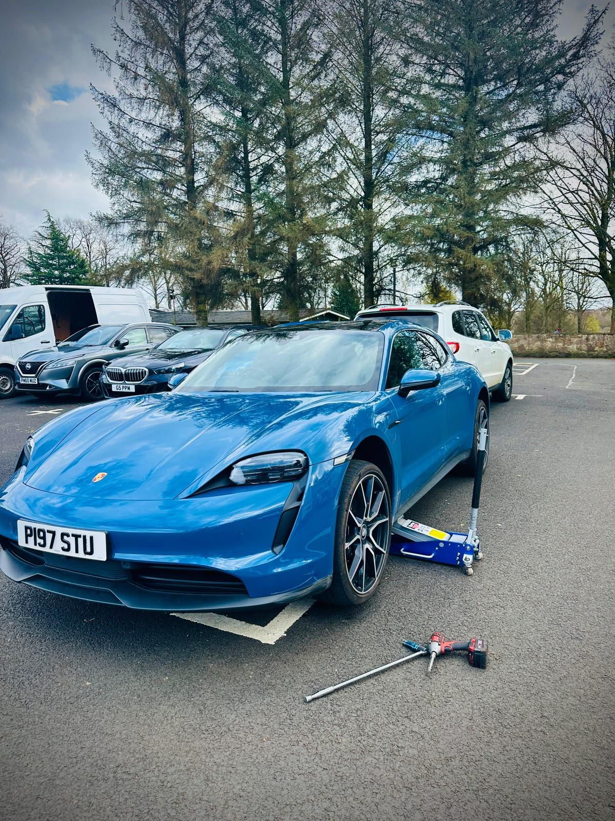 Blue Porsche receiving mobile tyre assistance